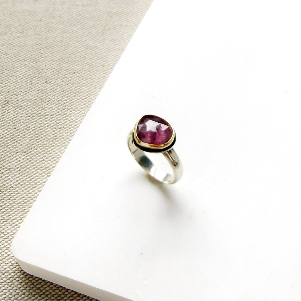 Rose cut pink sapphire mixed metal ring set on a white dish