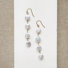 White coin pearl statement earrings on a white card