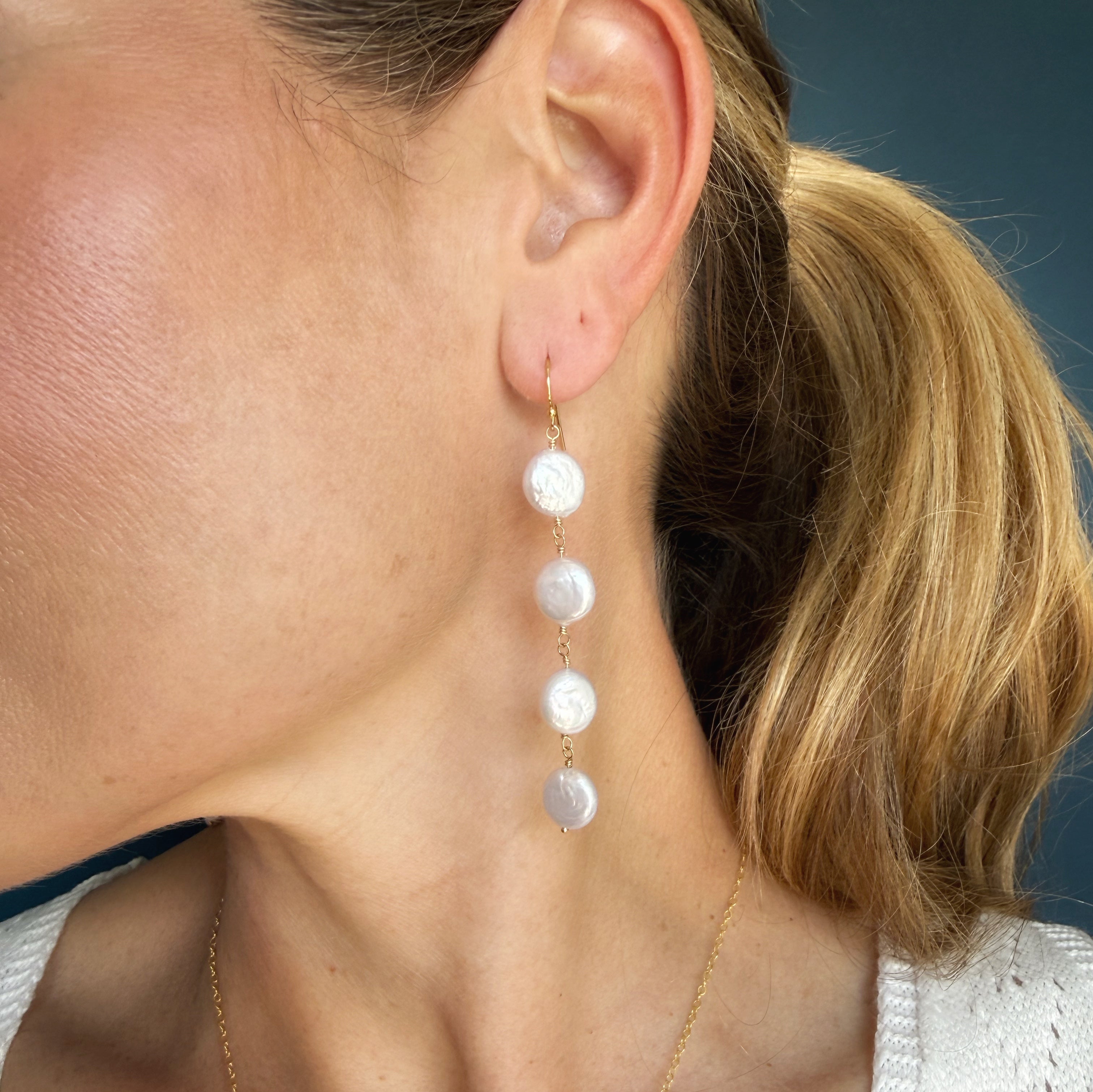 Close up of woman wearing white coin pearl earrings
