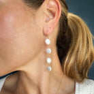 Close up of woman wearing white coin pearl earrings