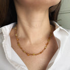 Necklace with citrine gems worn by a person in a white shirt.