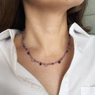 Necklace with purple gemstones worn by a person in a white shirt