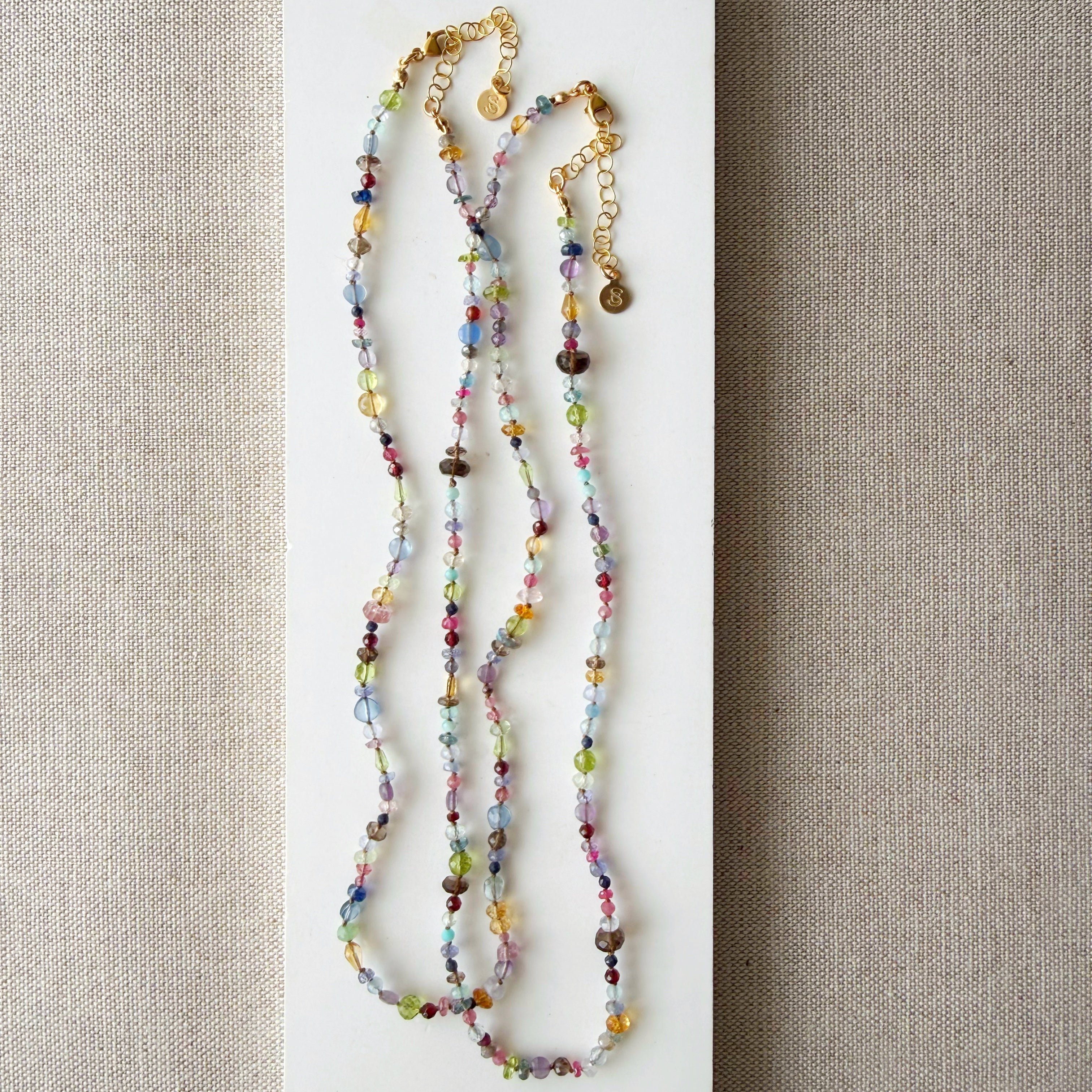 Multicolored gemstone necklace on a textured beige background