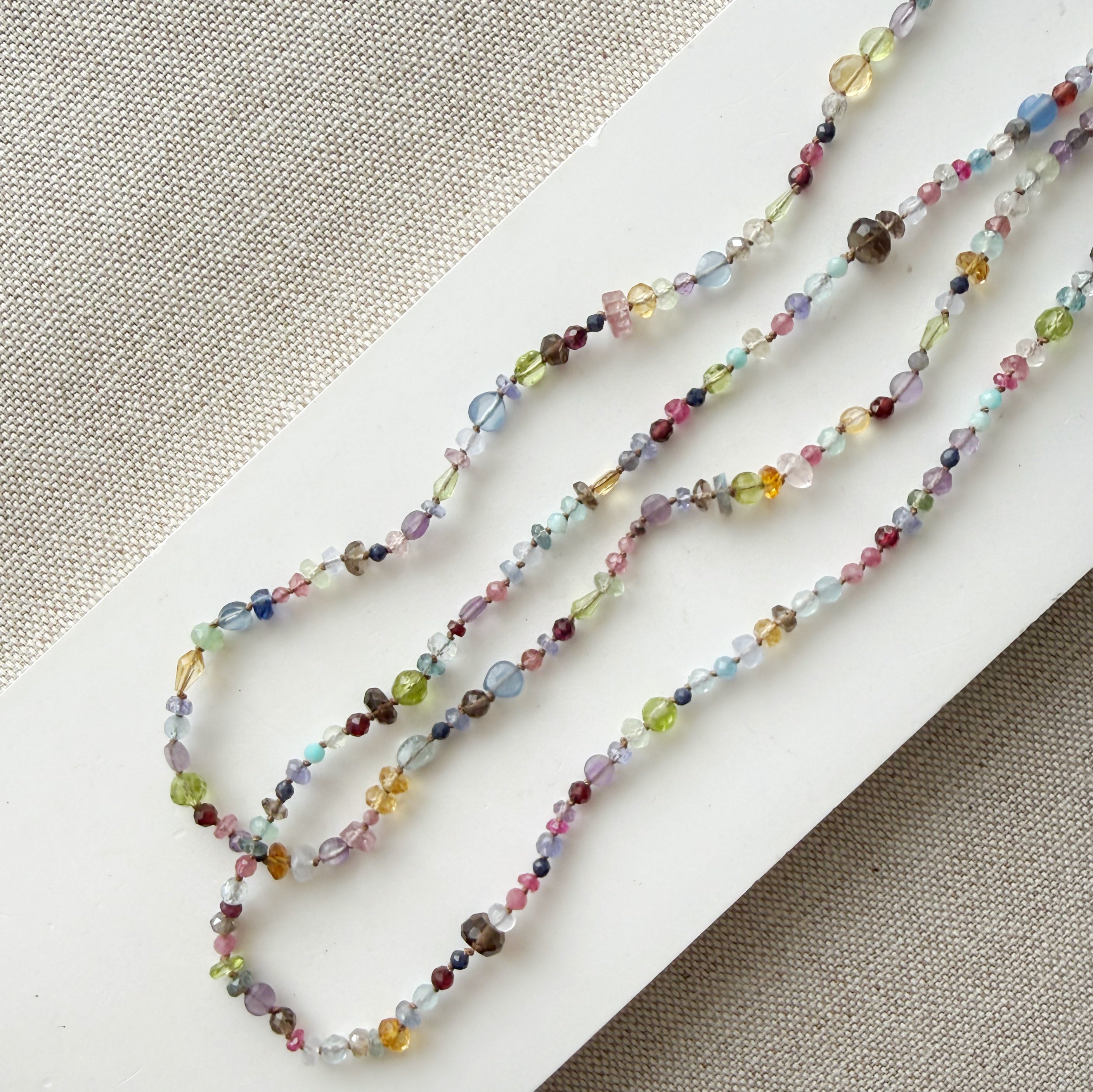 Multicolored gemstone necklace on a textured beige background