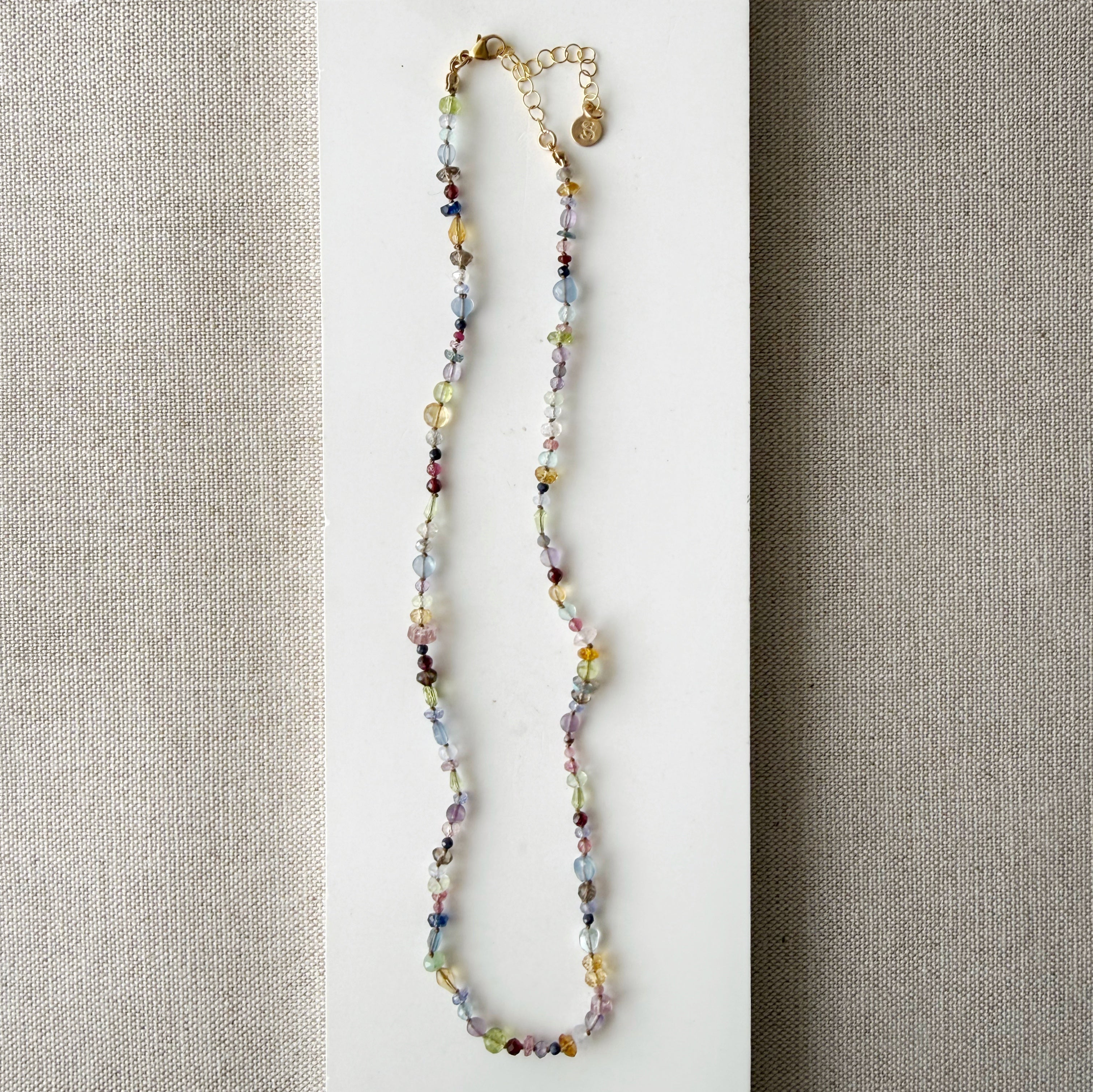 Multicolored gemstone necklace on a neutral fabric background