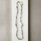 Multicolored gemstone necklace on a neutral fabric background