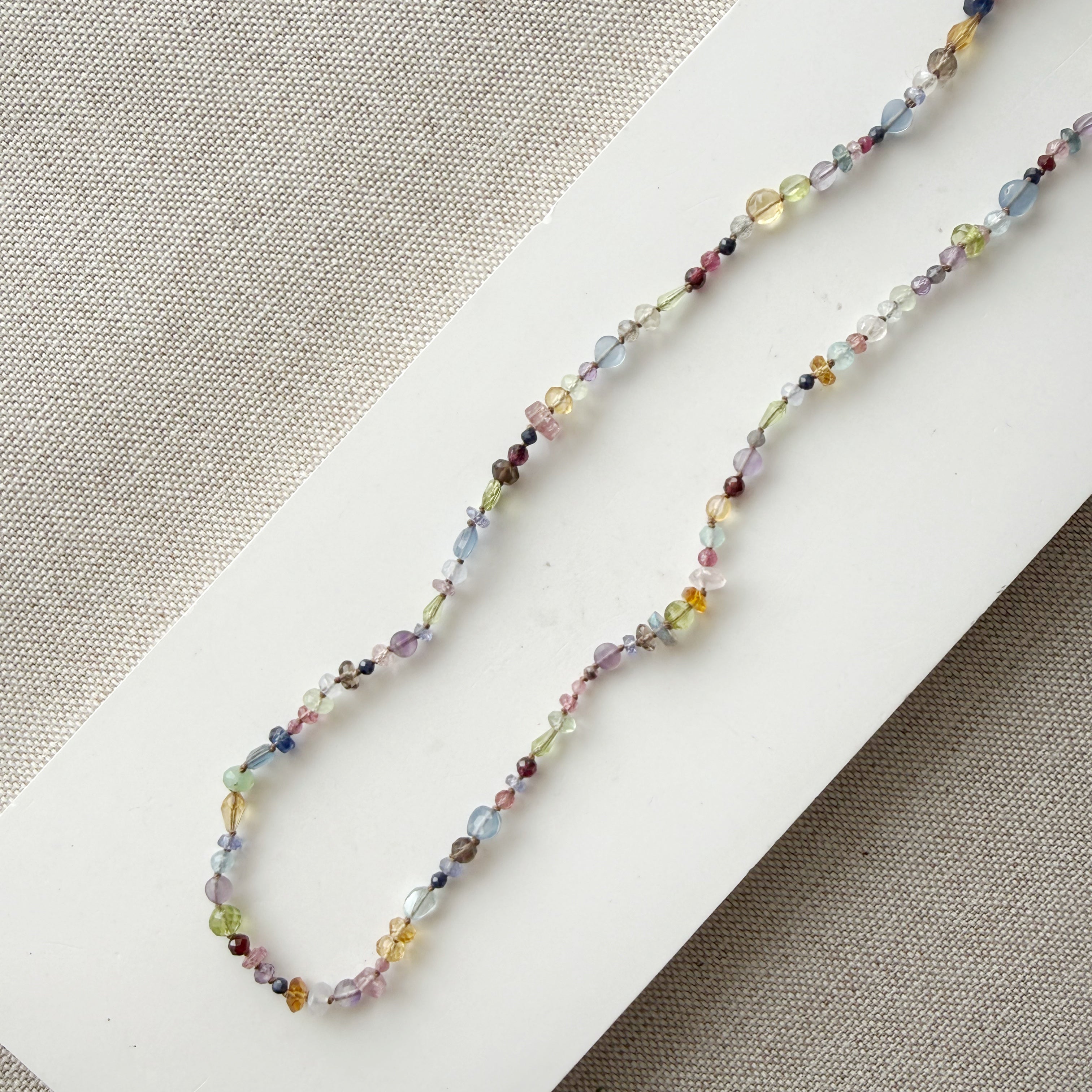 Multicolored gemstone necklace on a textured surface