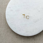 Tiny gold bar huggie style earrings on a white marble background