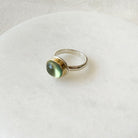 Ring with a green prehnite gemstone on a white plate on a white plate