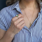 Person wearing a gold necklace and wearing a green prehnite gemstone ring.