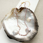Knotted necklace with tiny pink pearls in a shell