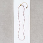 Knotted necklace with tiny pink pearls on a white card