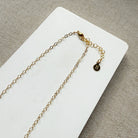 Clasp detail of necklace with multicolored gemstones on a white card