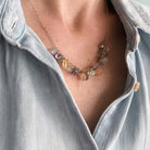 Necklace with multicolored gemstones worn by a person in a light blue top