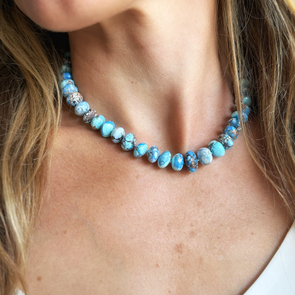 A close-up of a woman wearing a beaded necklace made of Golden Hills Turquoise.