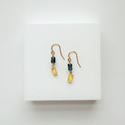 Pair of gold earrings with blue and yellow gems on a white background