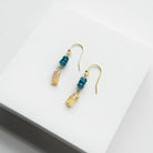 Gold earrings with blue and gold gemstones on a white surface