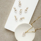 Carved leaf charm in rose quartz on a gold chain in a white dish