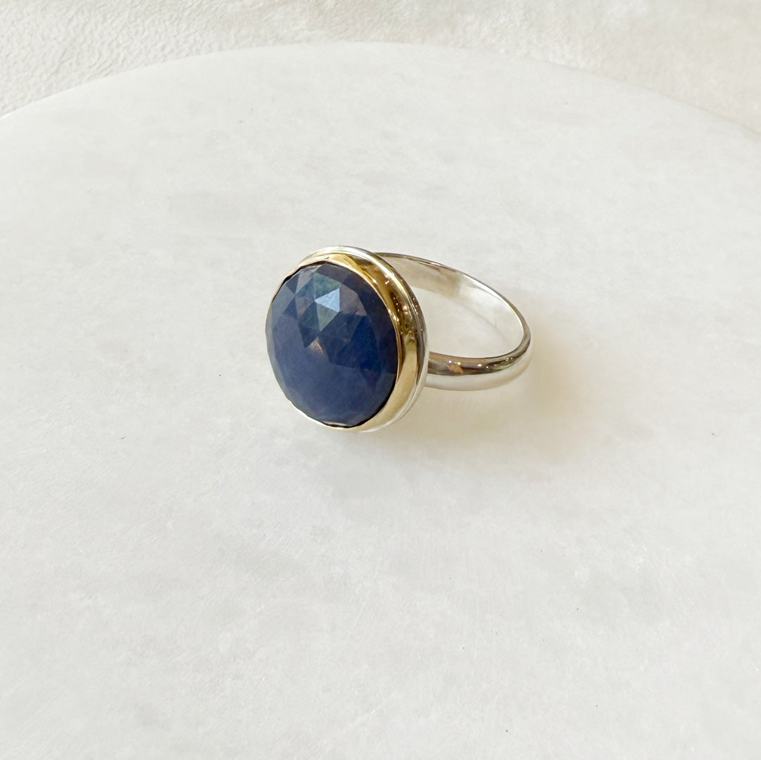 Round faceted sapphire ring on a white dish 