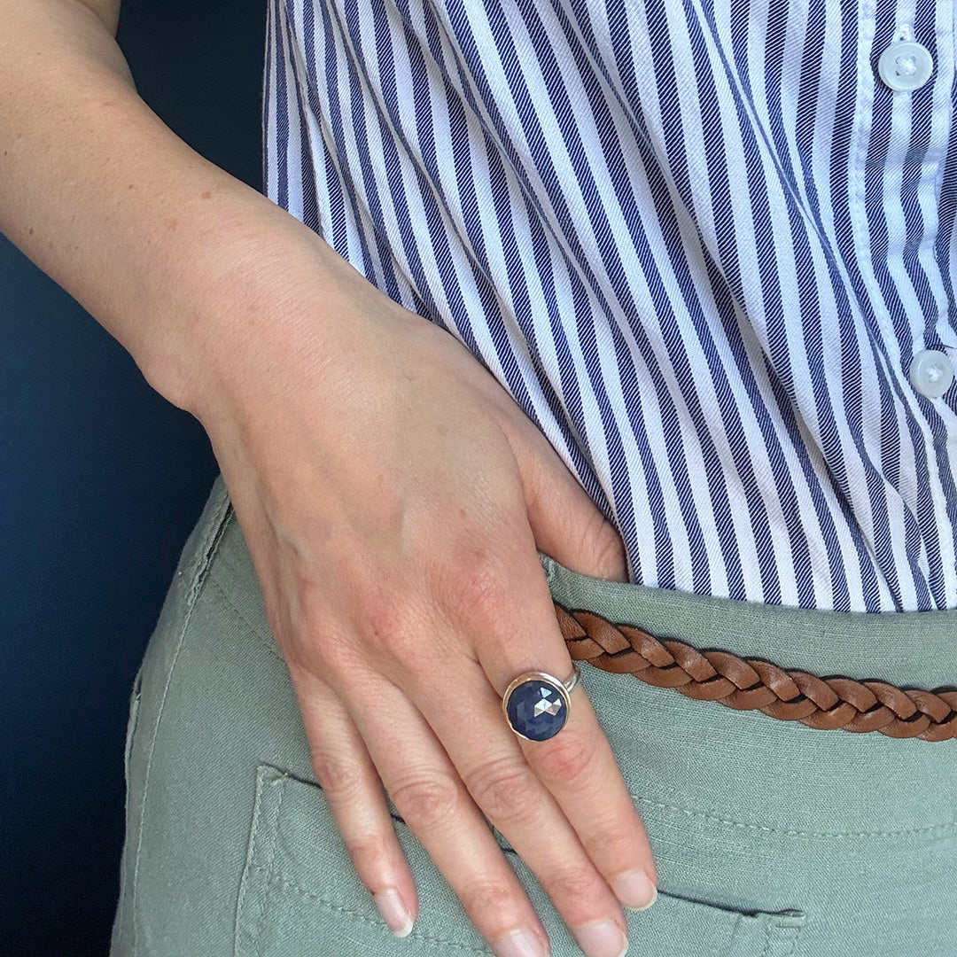 Close up of hand wearing round faceted sapphire ring 