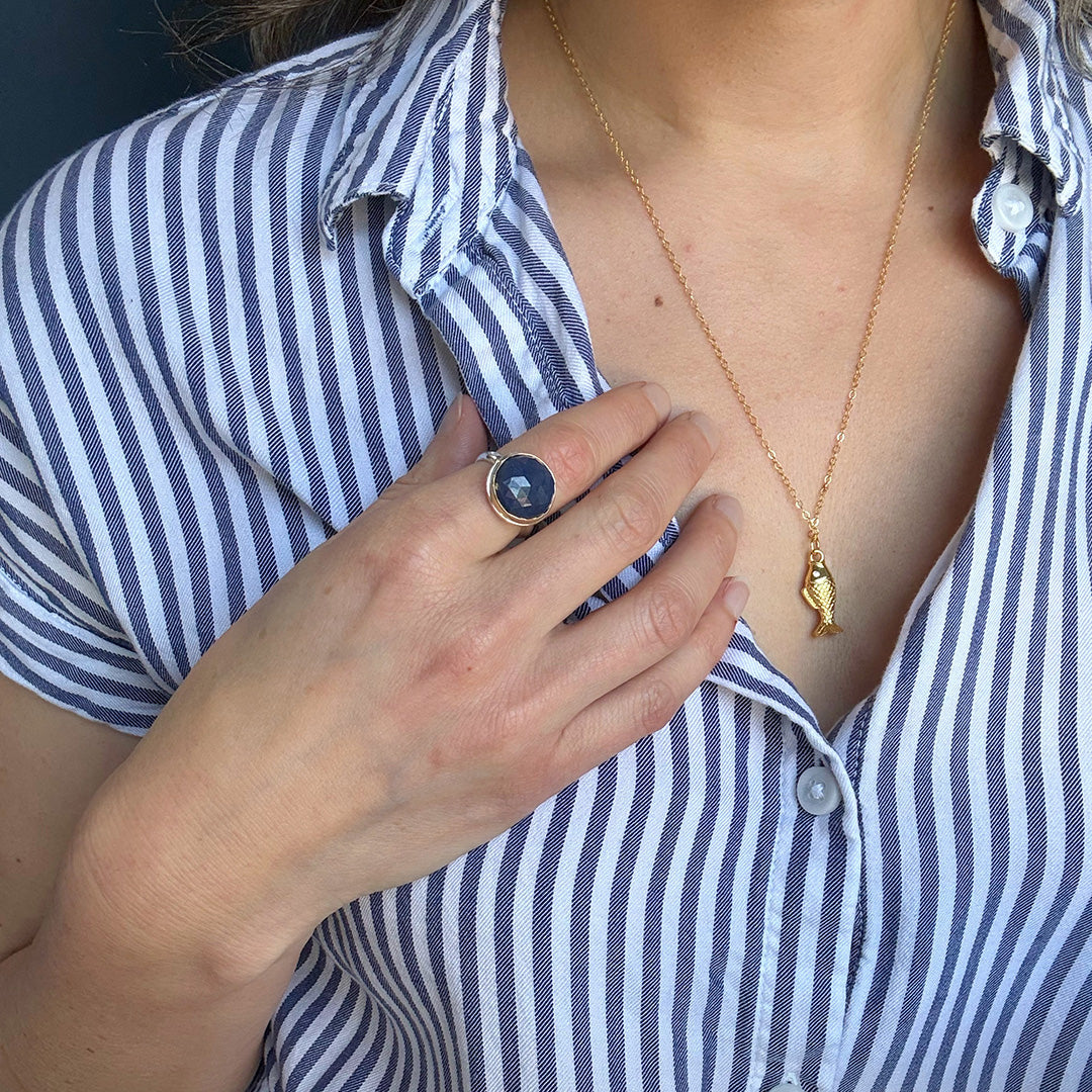 Close up of hand wearing round faceted sapphire ring 