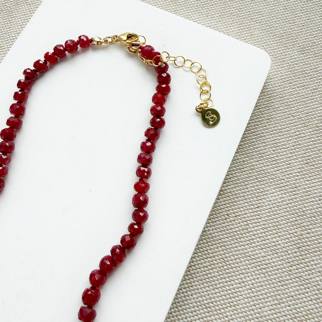 Clasp detail of ruby knotted necklace with turquoise carved flower pendant