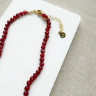 Clasp detail of ruby knotted necklace with turquoise carved flower pendant