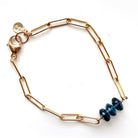 A gold paperclip chain bracelet with a small cluster of London Blue Topaz faceted beads, shown on a plain white background.