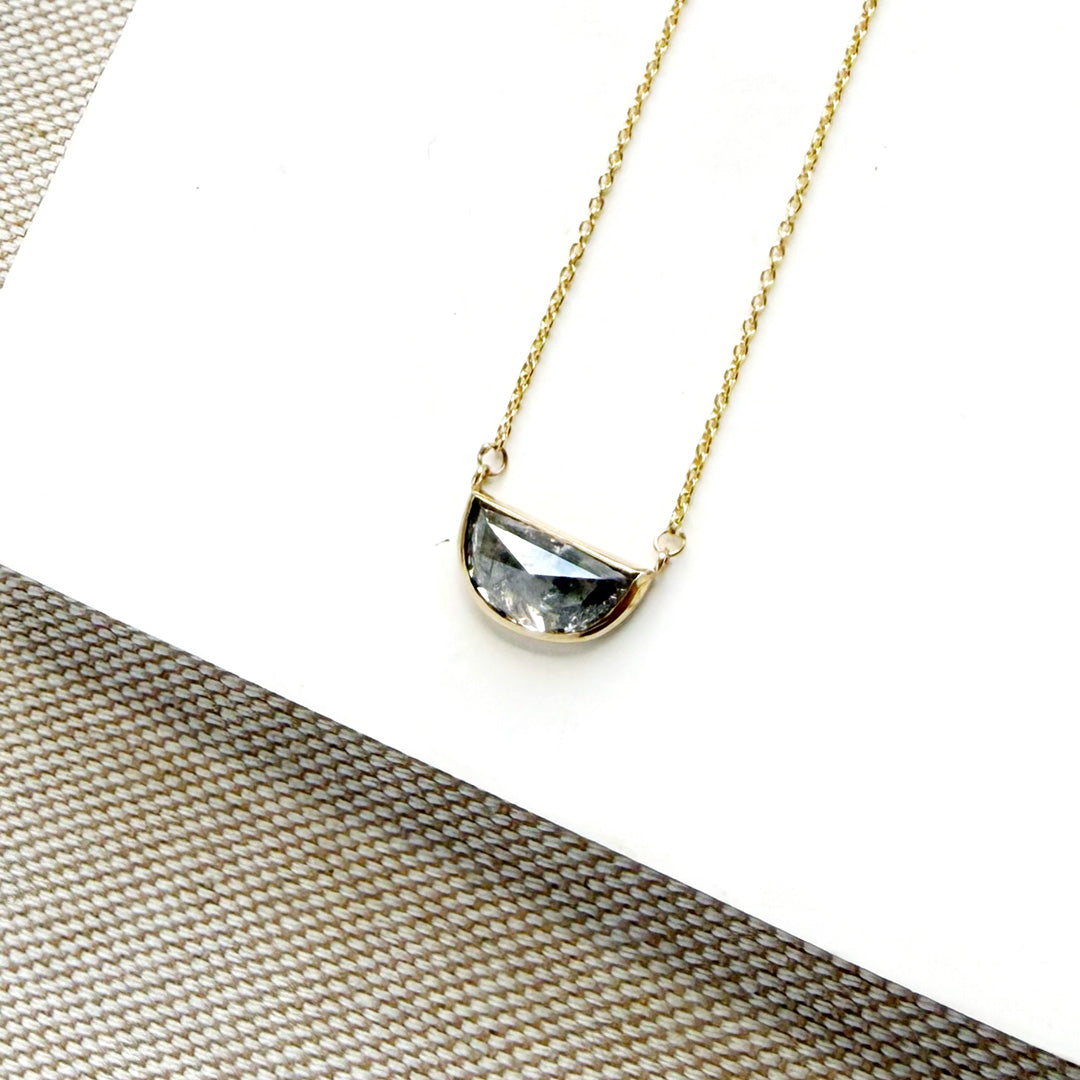 Solid gold necklace with a half moon salt and pepper diamond pendant on a white card.