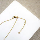 Clasp detail of solid gold necklace with a half moon salt and pepper diamond pendant on a white card