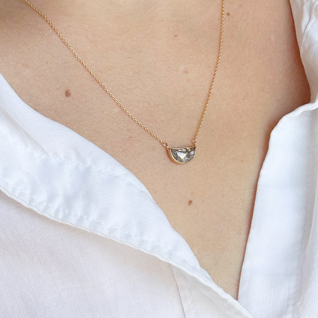 Solid gold necklace with a salt and pepper diamond pendant on a person wearing a white shirt.