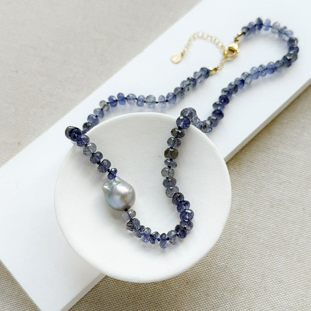 Knotted iolite gemstone necklace with gray baroque pearl in a white dish