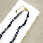 Clasp detail of a knotted iolite gemstone necklace with gray baroque pearl
