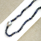 Knotted iolite gemstone necklace with gray baroque pearl on a white card
