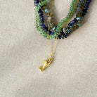 Gold necklace with a fish pendant on a beige fabric background