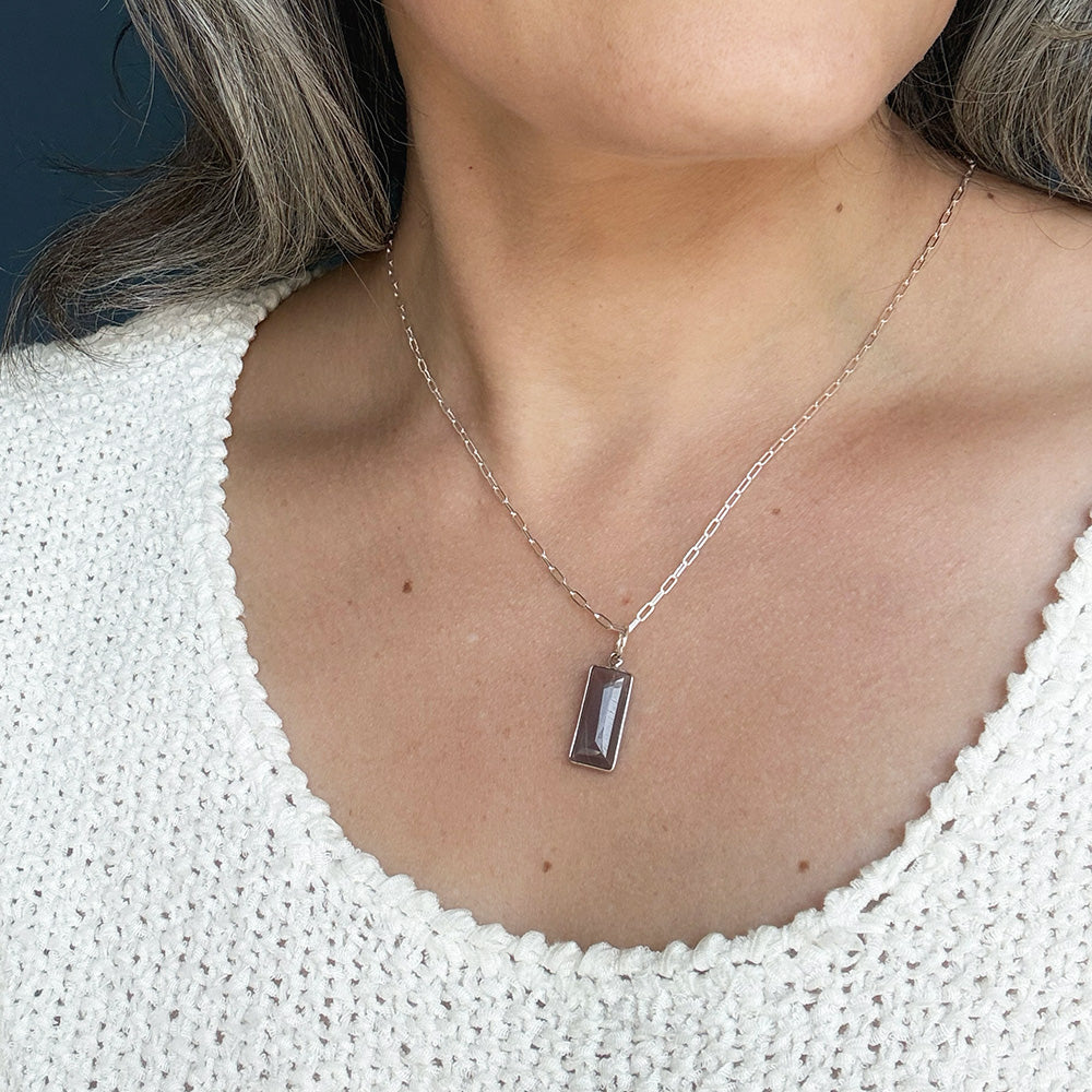 Woman wearing rectangular bezel set coffee moonstone charm in silver
