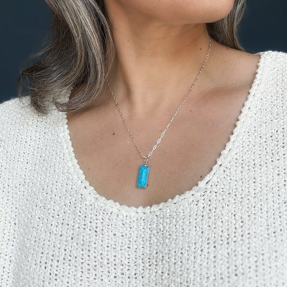 Woman wearing rectangular bezel set blue howlite charm in silver