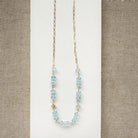 Necklace with blue topaz gemstones and gold chain on a white surface