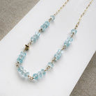 Necklace with blue topaz gemstones and gold chain on a white surface