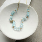 Necklace with blue topaz gemstones and gold chain in a white dish