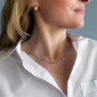 Woman wearing a blue topaz gemstone necklace and earrings against a light blue background