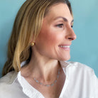 Woman wearing a blue topaz gemstone necklace and earrings against a light blue background