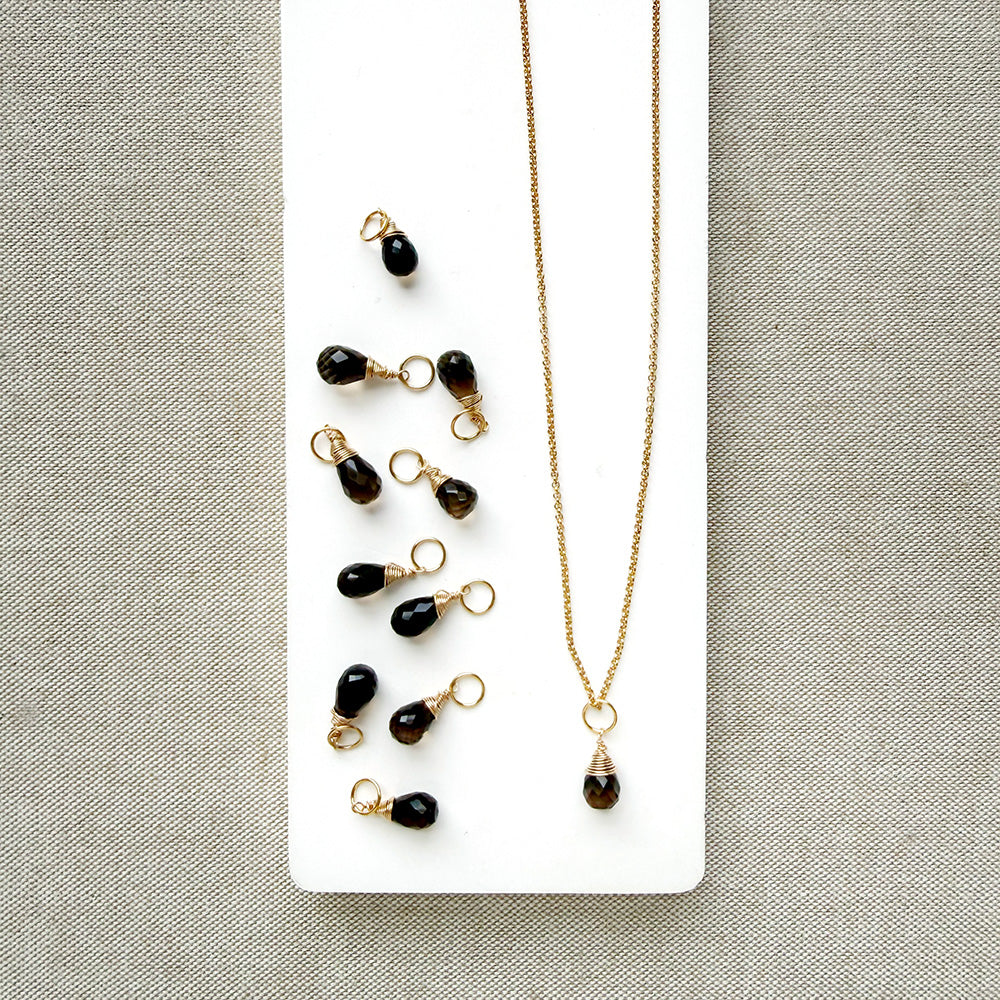Smokey Quartz charm on a gold chain in a white dish