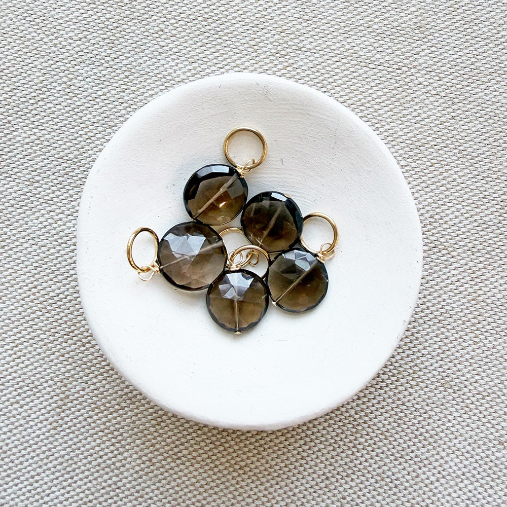 White dish of round smoky quartz charms