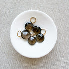 White dish of round smoky quartz charms