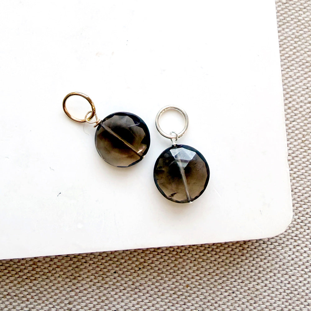 Round smoky quartz charms on white background
