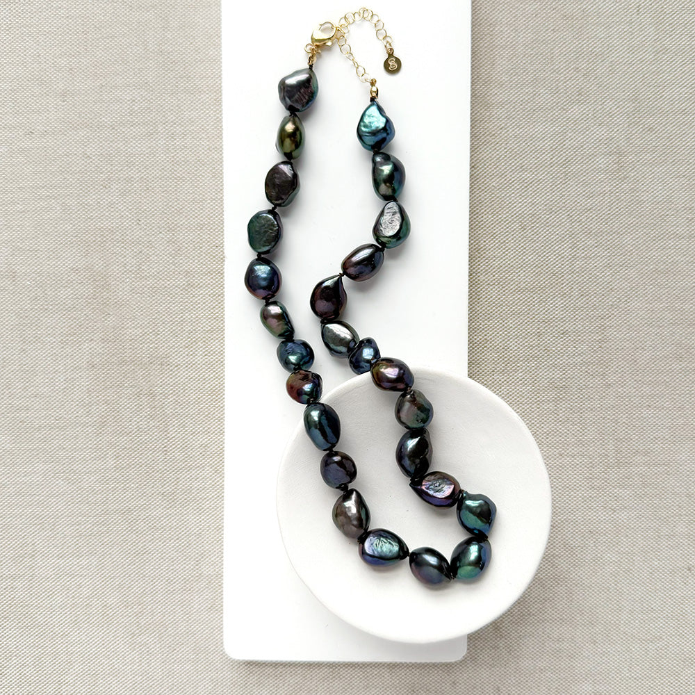 Peacock pearl statement necklace in a white dish