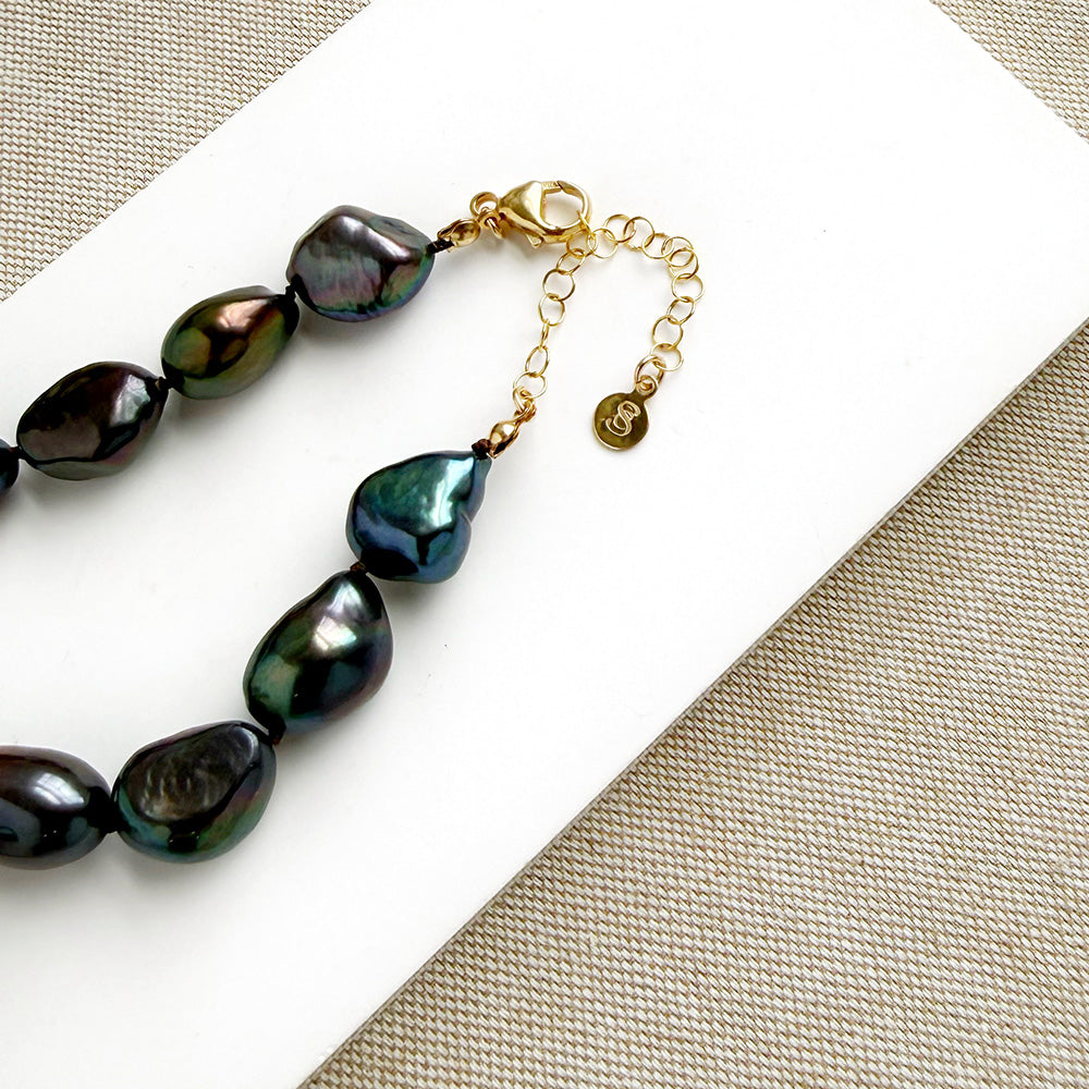 Peacock pearl statement necklace on a white dish