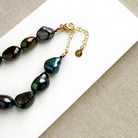 Peacock pearl statement necklace on a white dish