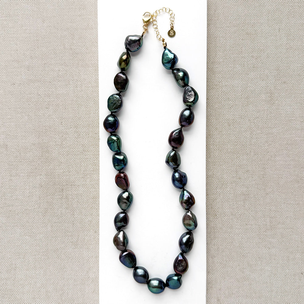 Peacock pearl statement necklace on a white dish